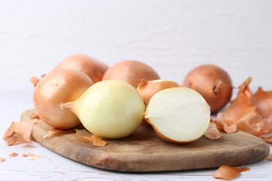 Photo of Fresh onions with peels on light table, closeup