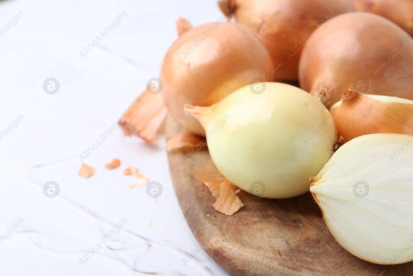 Photo of Fresh onions with peels on light textured table, closeup. Space for text