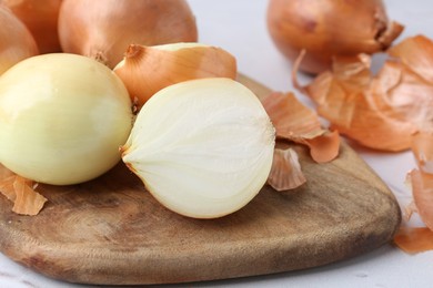 Photo of Fresh onions with peels on light table, closeup