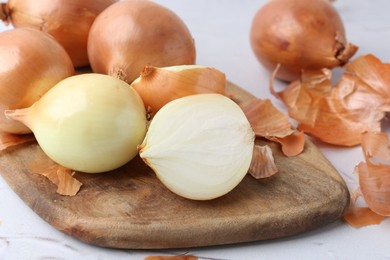 Photo of Fresh onions with peels on light table, closeup