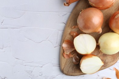 Photo of Fresh onions with peels on light textured table, top view. Space for text