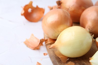 Fresh onions with peels on light table, closeup