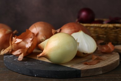 Photo of Fresh onions with peels on wooden table, closeup