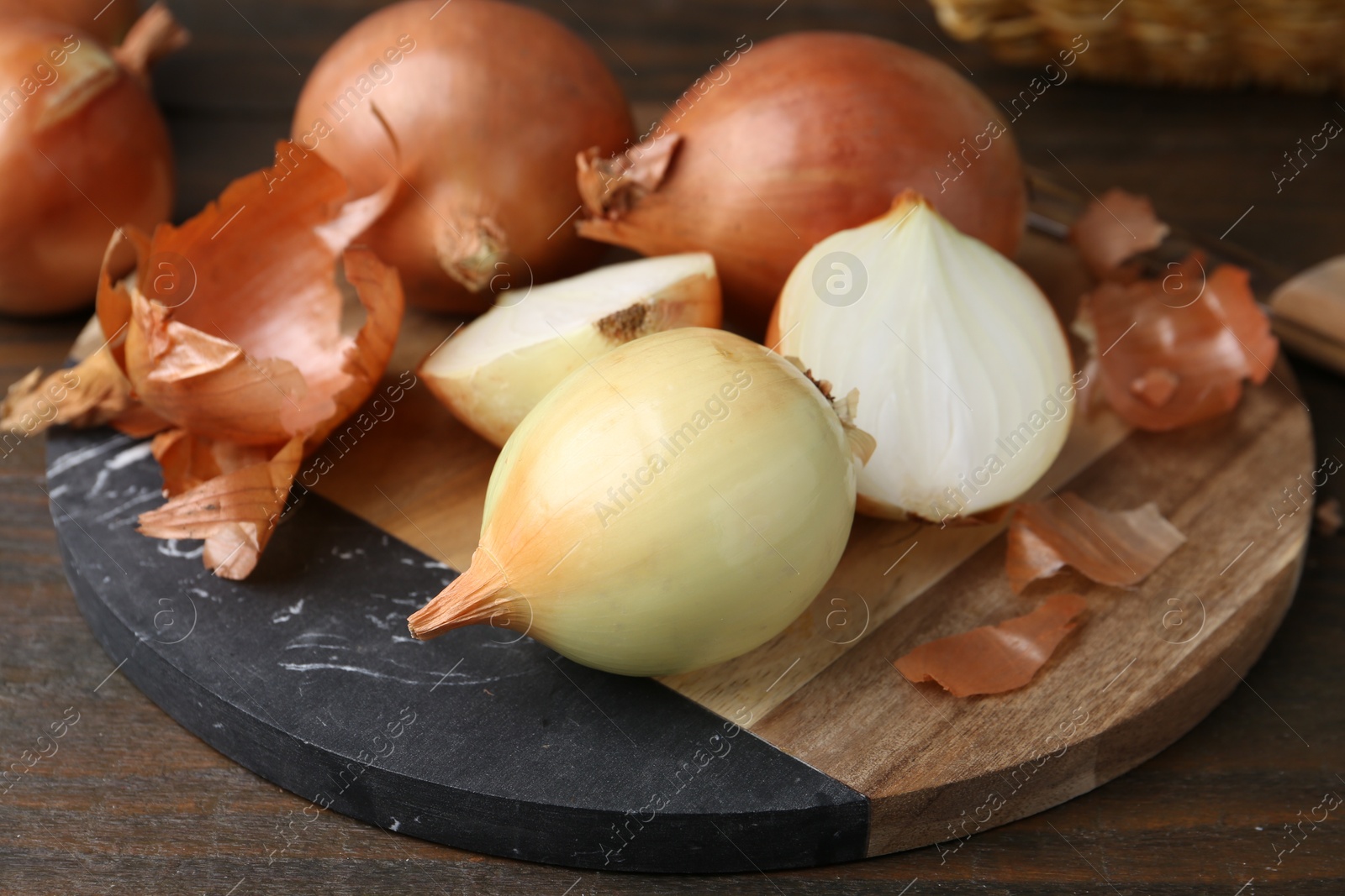 Photo of Fresh onions with peels on wooden table, closeup