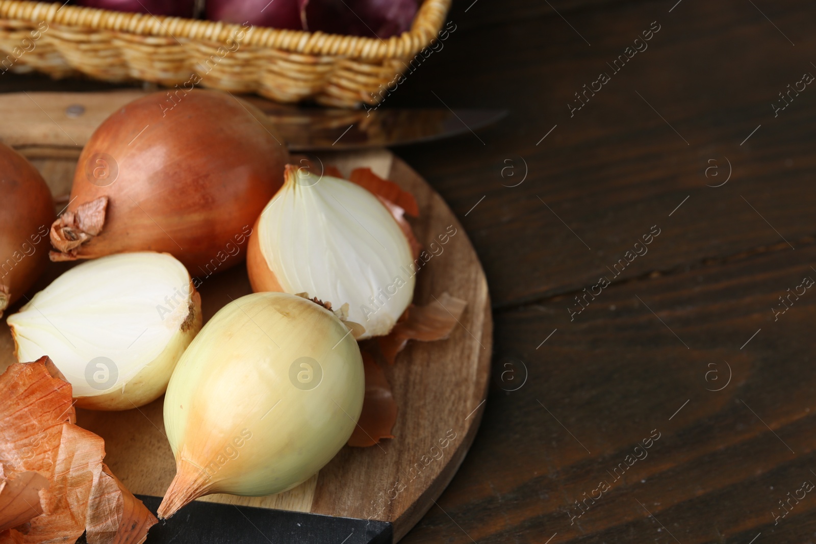 Photo of Fresh onions with peels on wooden table, closeup. Space for text