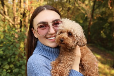 Smiling woman with cute dog in autumn park