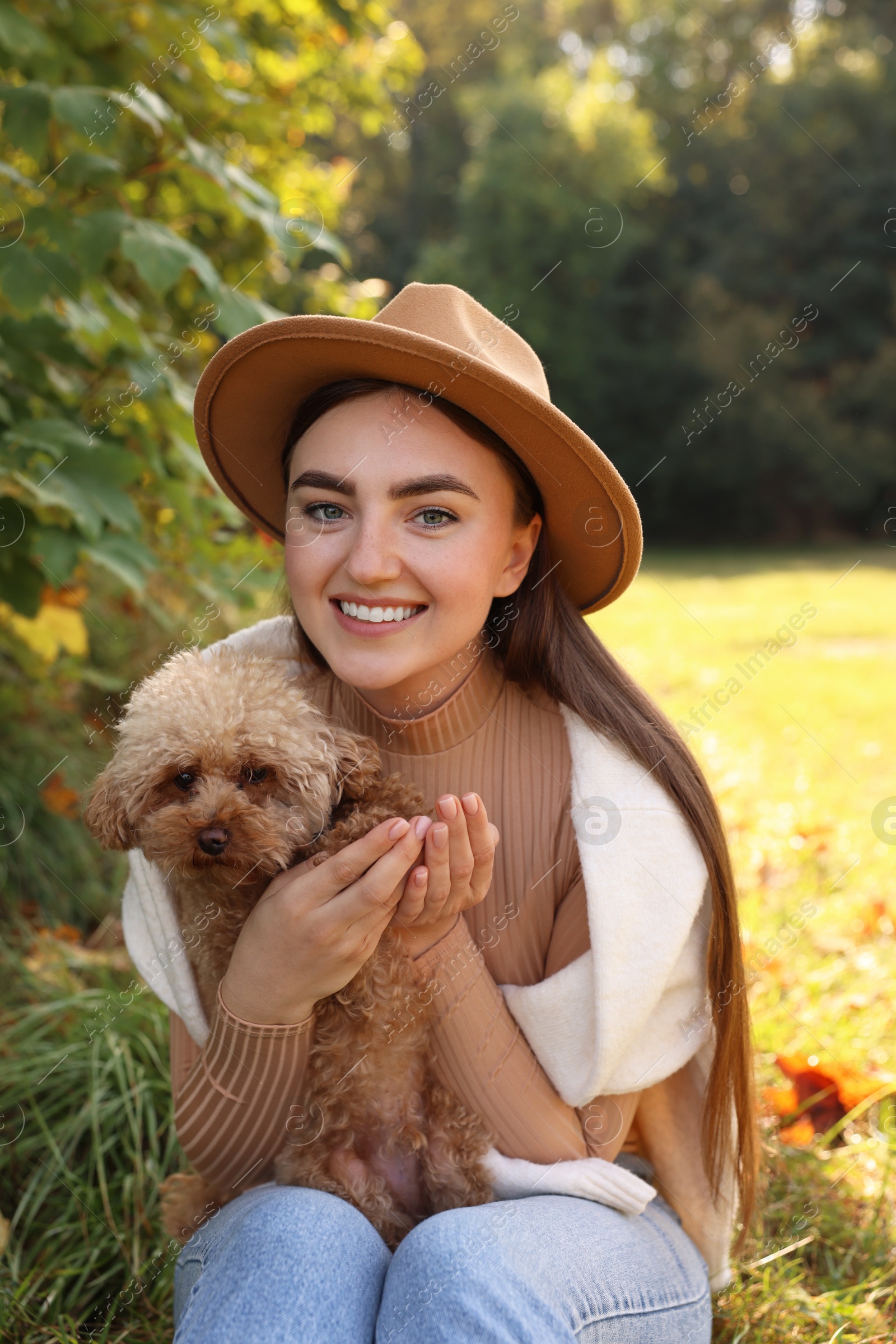 Photo of Smiling woman with cute dog in autumn park