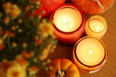 Photo of Burning candles, flowers and pumpkins on table, above view. Autumn atmosphere