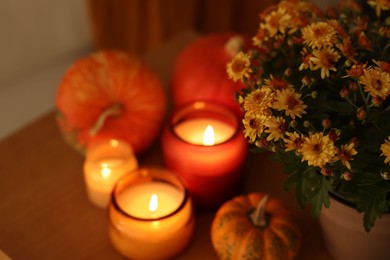 Photo of Burning candles, flowers and pumpkins on table, closeup. Autumn atmosphere