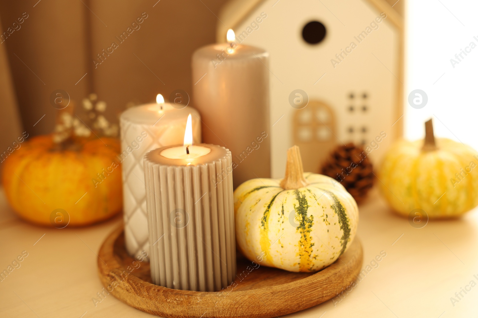 Photo of Burning candles and pumpkins on white table, closeup. Autumn atmosphere