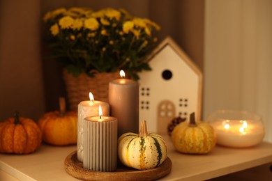 Photo of Burning candles, pumpkins and autumn decor on white table