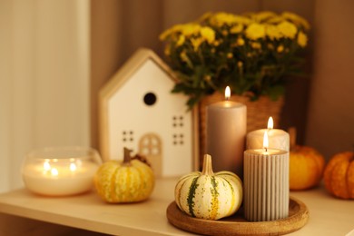 Photo of Burning candles, pumpkins and autumn decor on white table