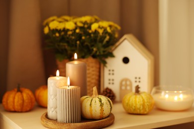 Photo of Burning candles, pumpkins and autumn decor on white table