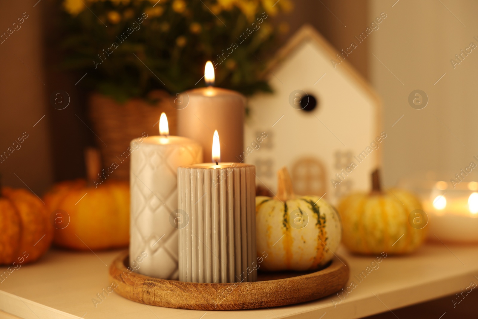 Photo of Burning candles and pumpkins on white table, closeup. Autumn atmosphere