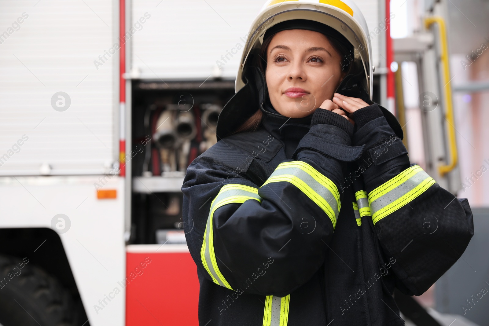 Photo of Firefighter in uniform wearing helmet near fire truck outdoors