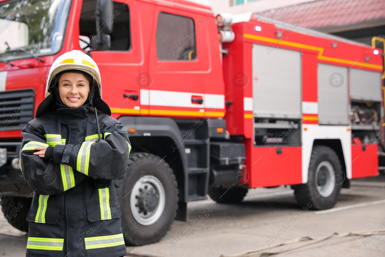 Photo of Portrait of firefighter in uniform and helmet near fire truck outdoors