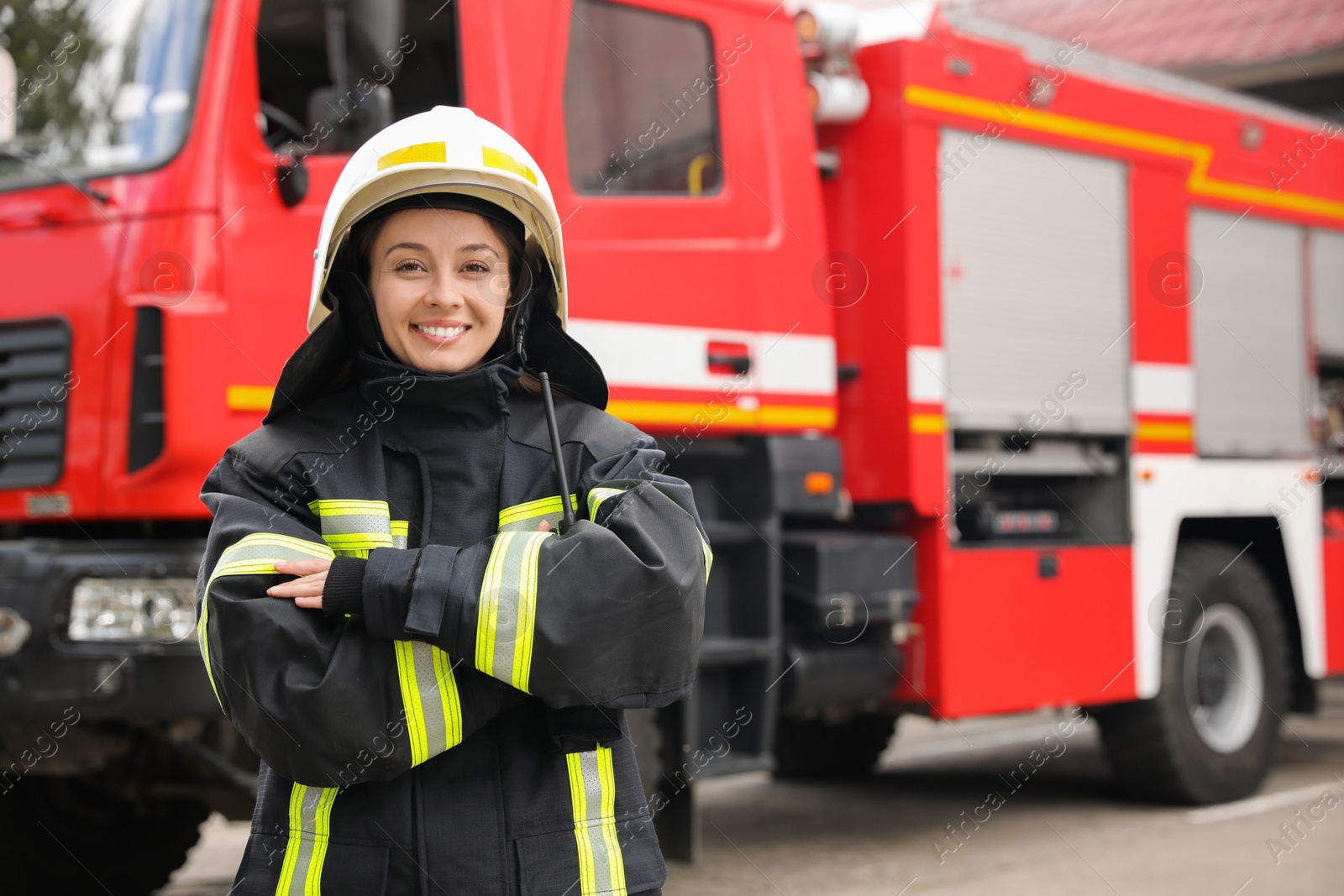 Photo of Portrait of firefighter in uniform and helmet near fire truck outdoors