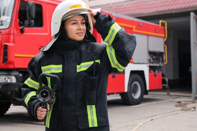 Firefighter in uniform with high pressure water jet near fire truck outdoors