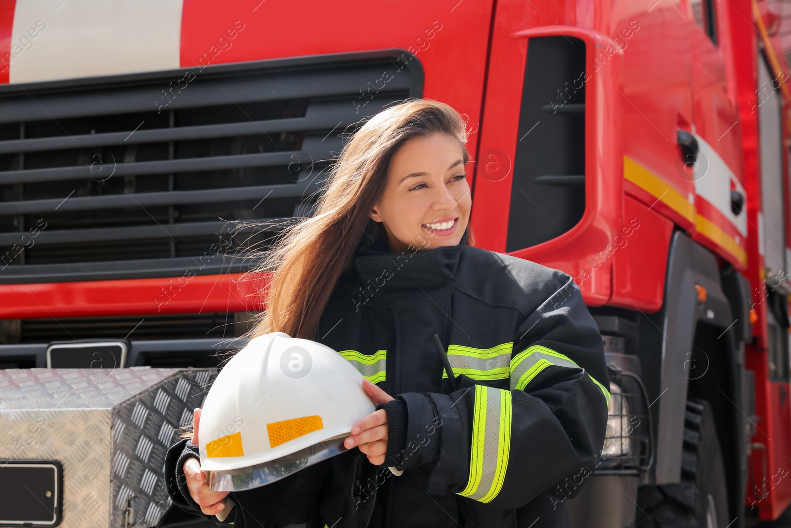 Photo of Portrait of firefighter in uniform with helmet near fire truck outdoors