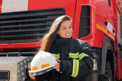 Portrait of firefighter in uniform with helmet near fire truck outdoors