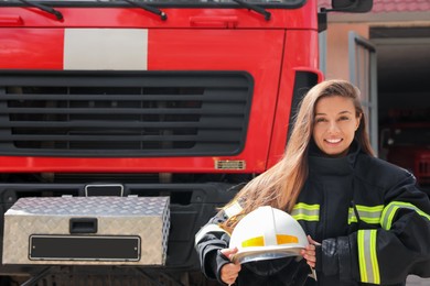 Portrait of firefighter in uniform with helmet near fire truck outdoors