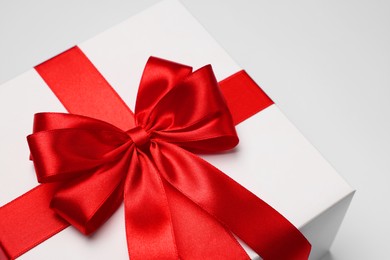 Photo of Gift box with red bow on light grey background, closeup