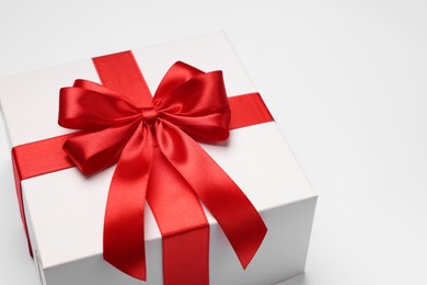 Photo of Gift box with red bow on light grey background, closeup