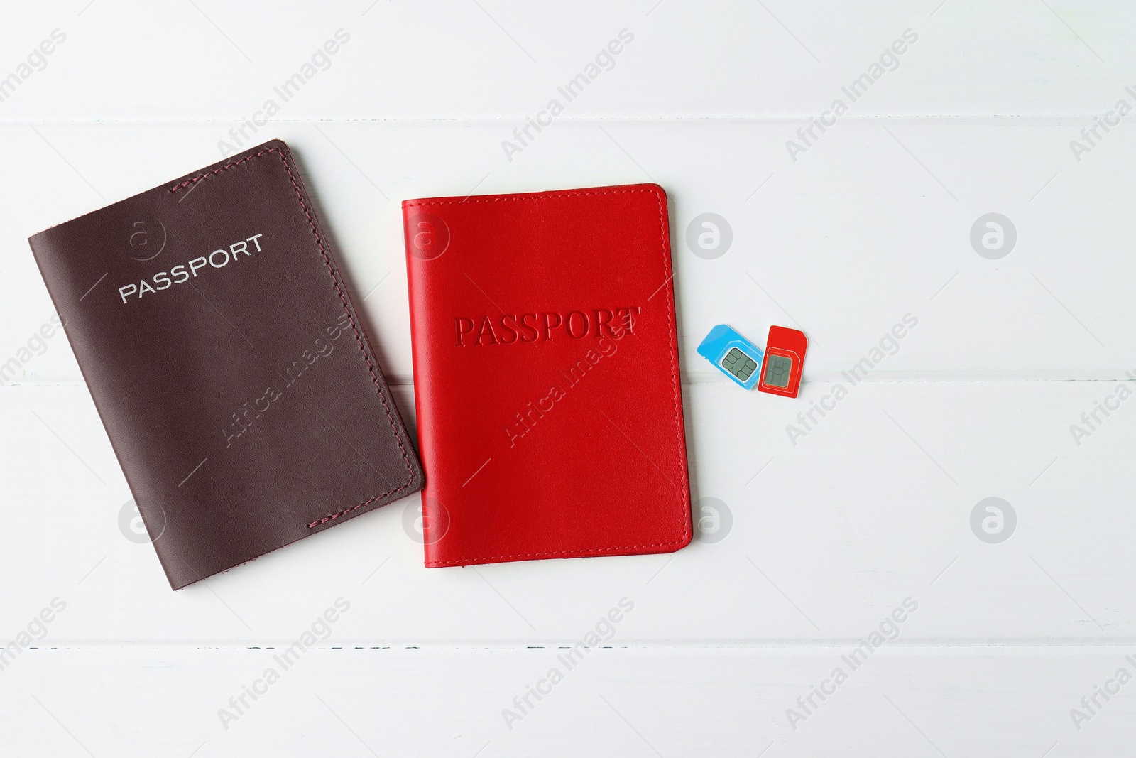 Photo of Passports and SIM cards on white wooden table, flat lay