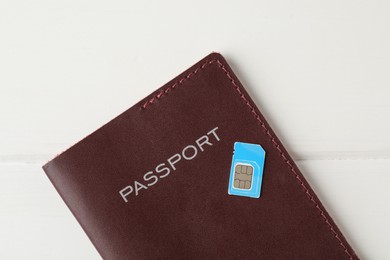 Passport and SIM card on white wooden table, top view