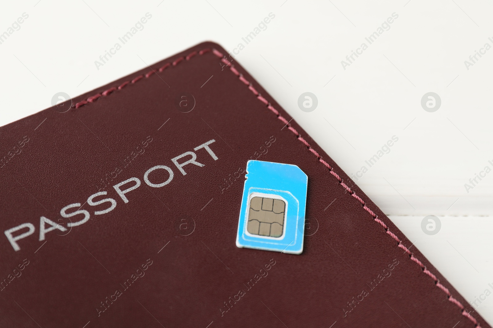 Photo of Passport and SIM card on white table, closeup