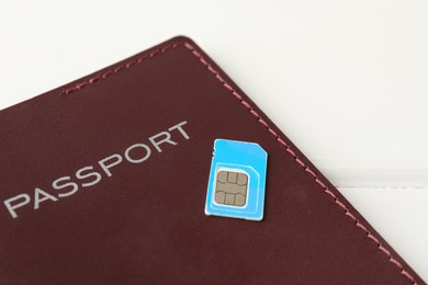 Passport and SIM card on white table, closeup