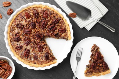 Photo of Delicious pecan pie, fresh nuts and cake server on dark gray textured table, top view