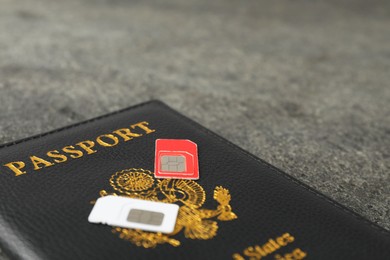 Passport and SIM cards on grey table, closeup