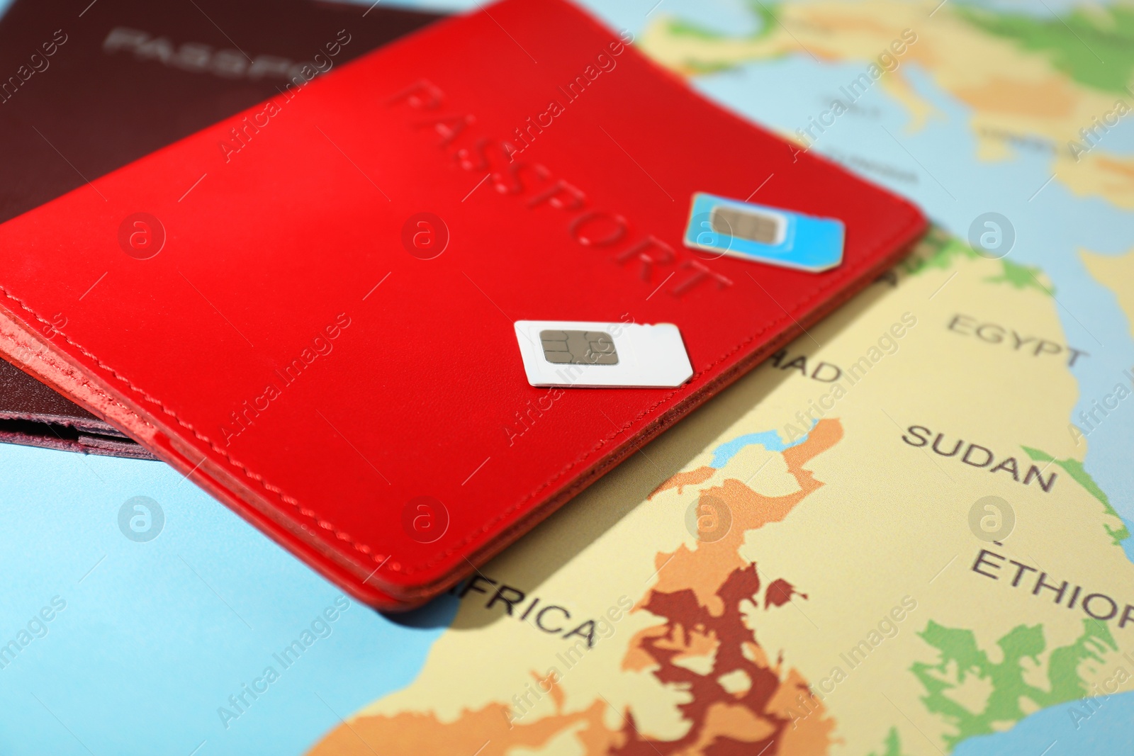 Photo of Modern SIM cards and passports on world map, closeup