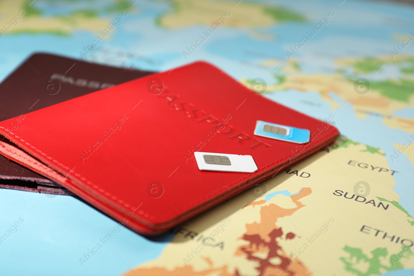 Photo of Modern SIM cards and passports on world map, closeup