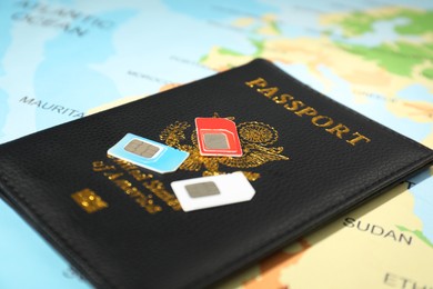 Photo of Modern SIM cards and passport on world map, closeup