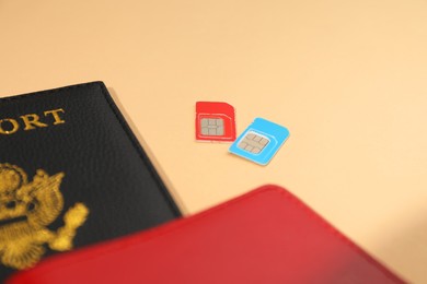 Photo of Modern SIM cards and passport on beige background, closeup