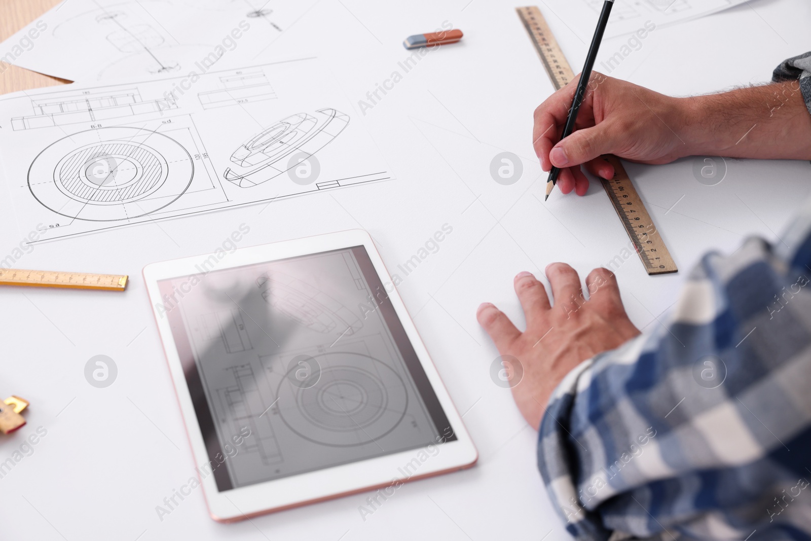 Photo of Architect making engineering drawing at table in office, closeup