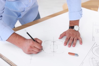 Architect making engineering drawing at wooden table in office, closeup