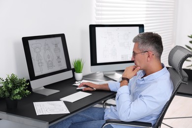 Photo of Architect checking engineering drawing at table in office