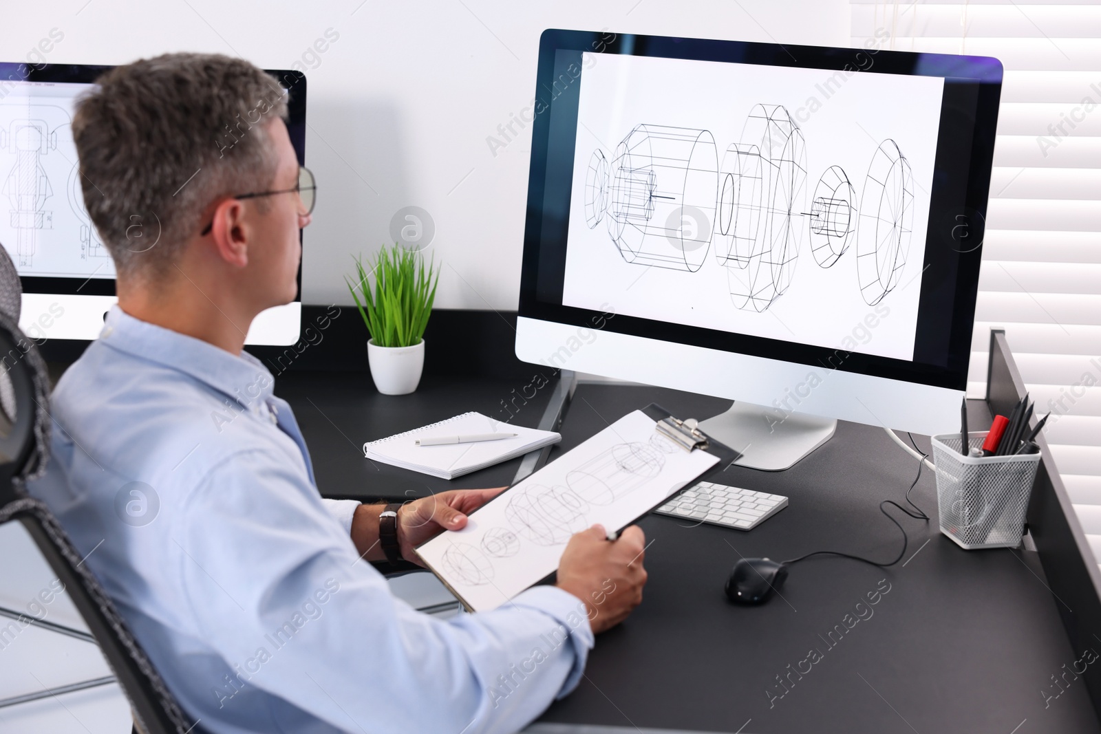 Photo of Architect checking engineering drawing at table in office