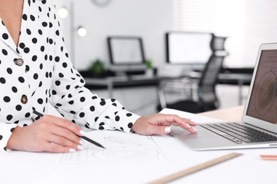 Photo of Architect making engineering drawing at table in office, closeup