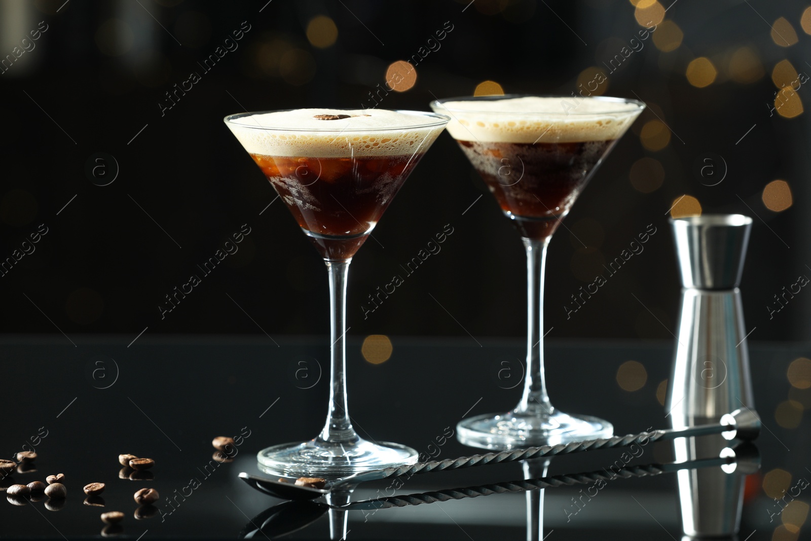 Photo of Refreshing cocktails in glasses, jigger, spoon and coffee beans on black table