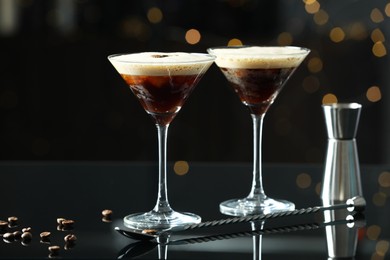 Photo of Refreshing cocktails in glasses, jigger, spoon and coffee beans on black table