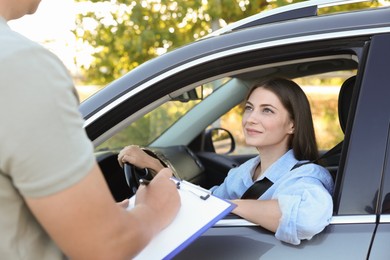 Examiner near car with student during test at driving school