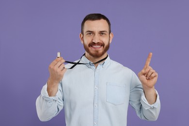 Happy young man with whistle on purple background