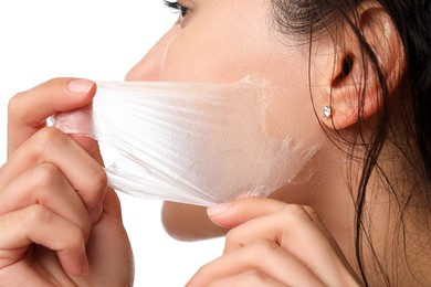 Woman peeling off face mask on white background, closeup