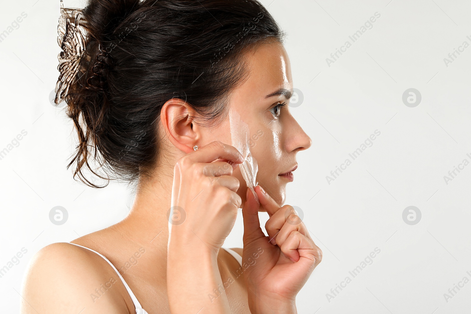 Photo of Beautiful woman peeling off face mask on light grey background. Space for text