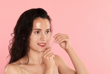 Smiling woman peeling off face mask on pink background. Space for text