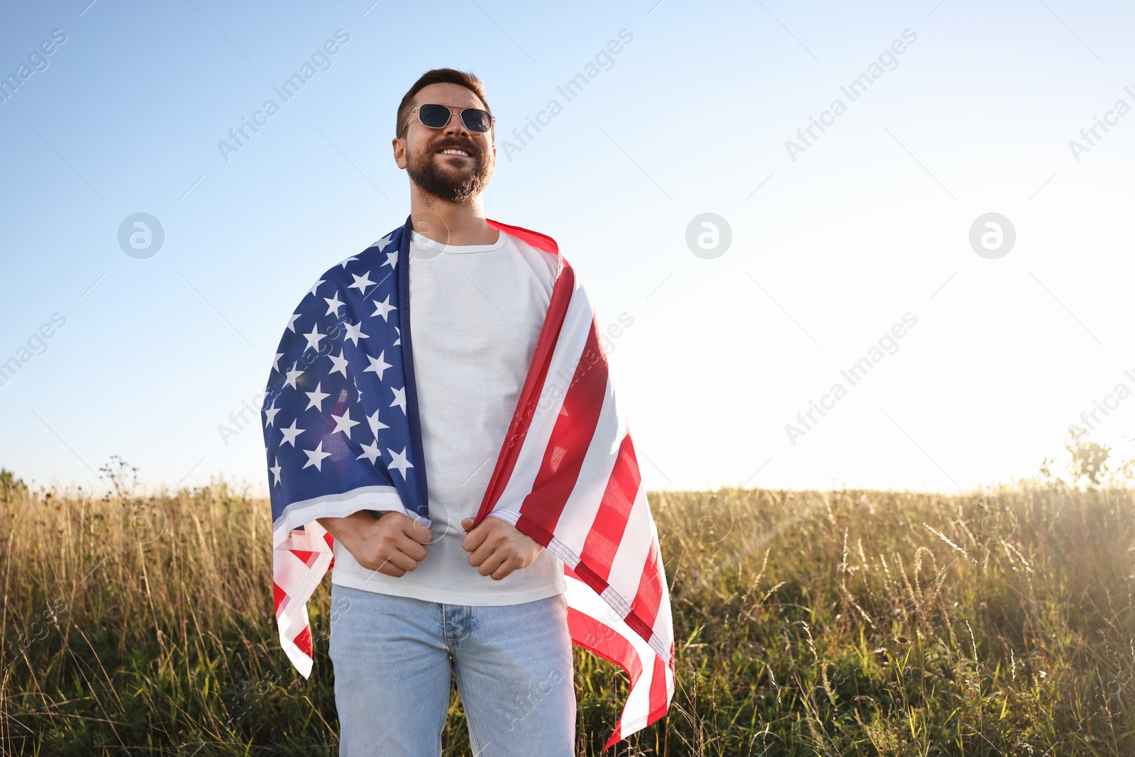 Photo of Happy man with flag of USA outdoors, low angle view. Space for text